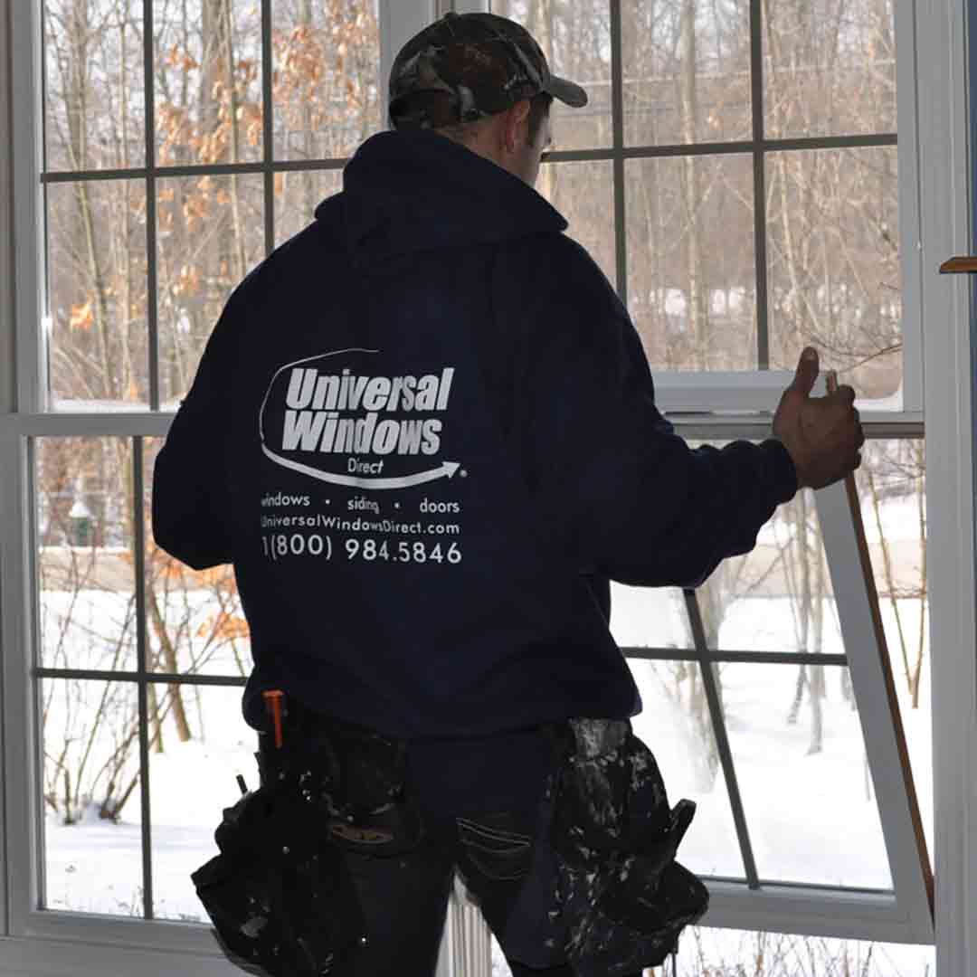 uwd worker installing bottom sash of new double hung window