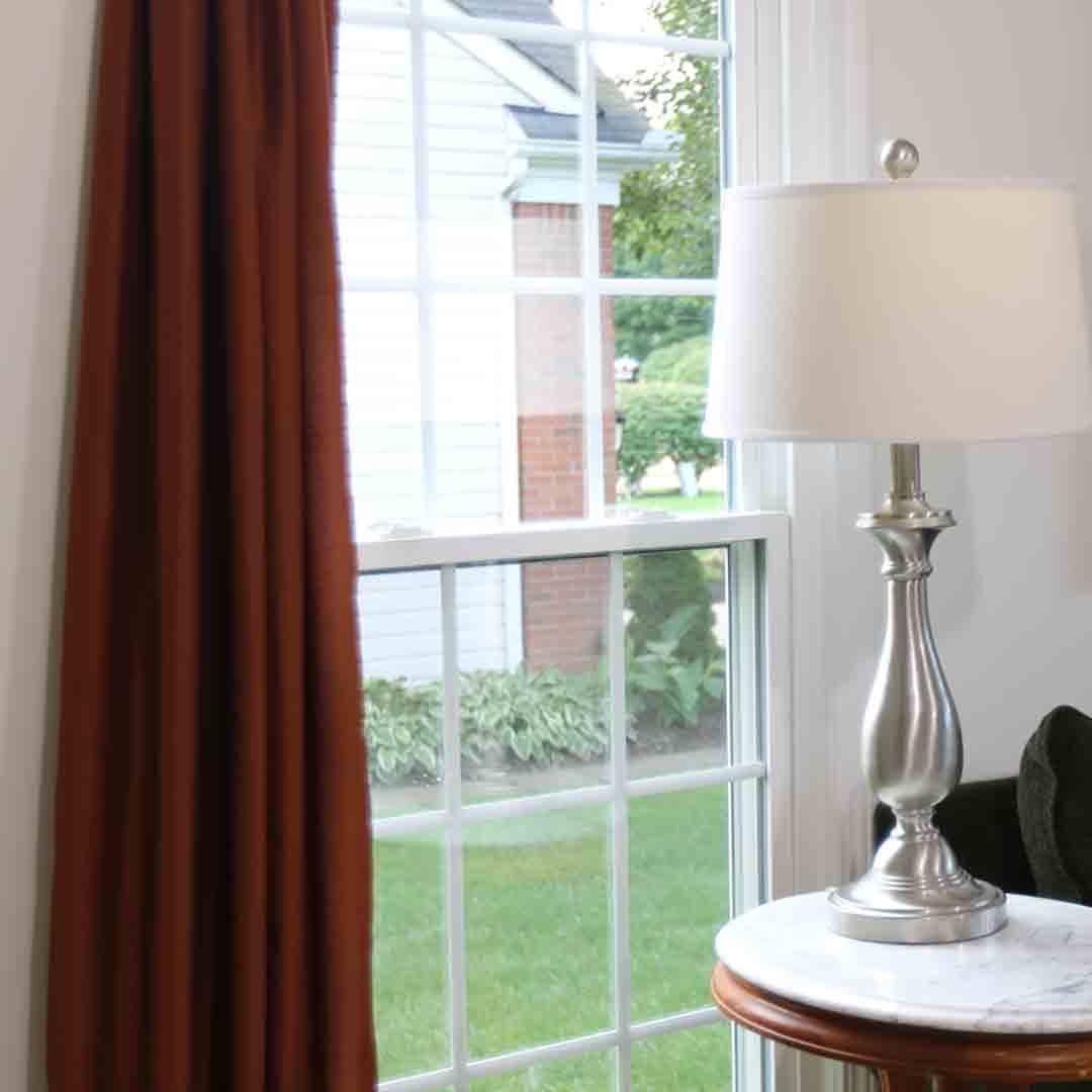 Lamp and table in front of double hung window with grids