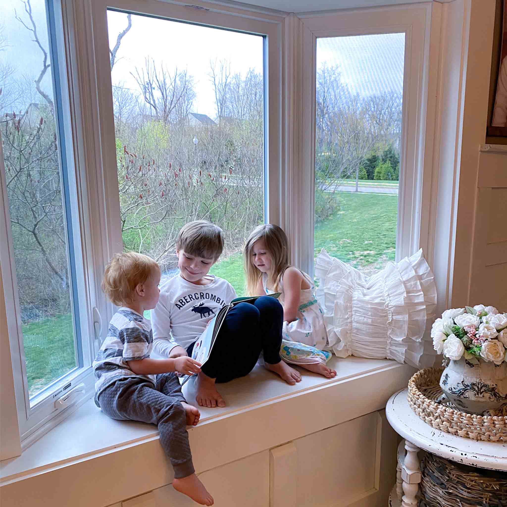 Kids sitting in bay window seat reading a book