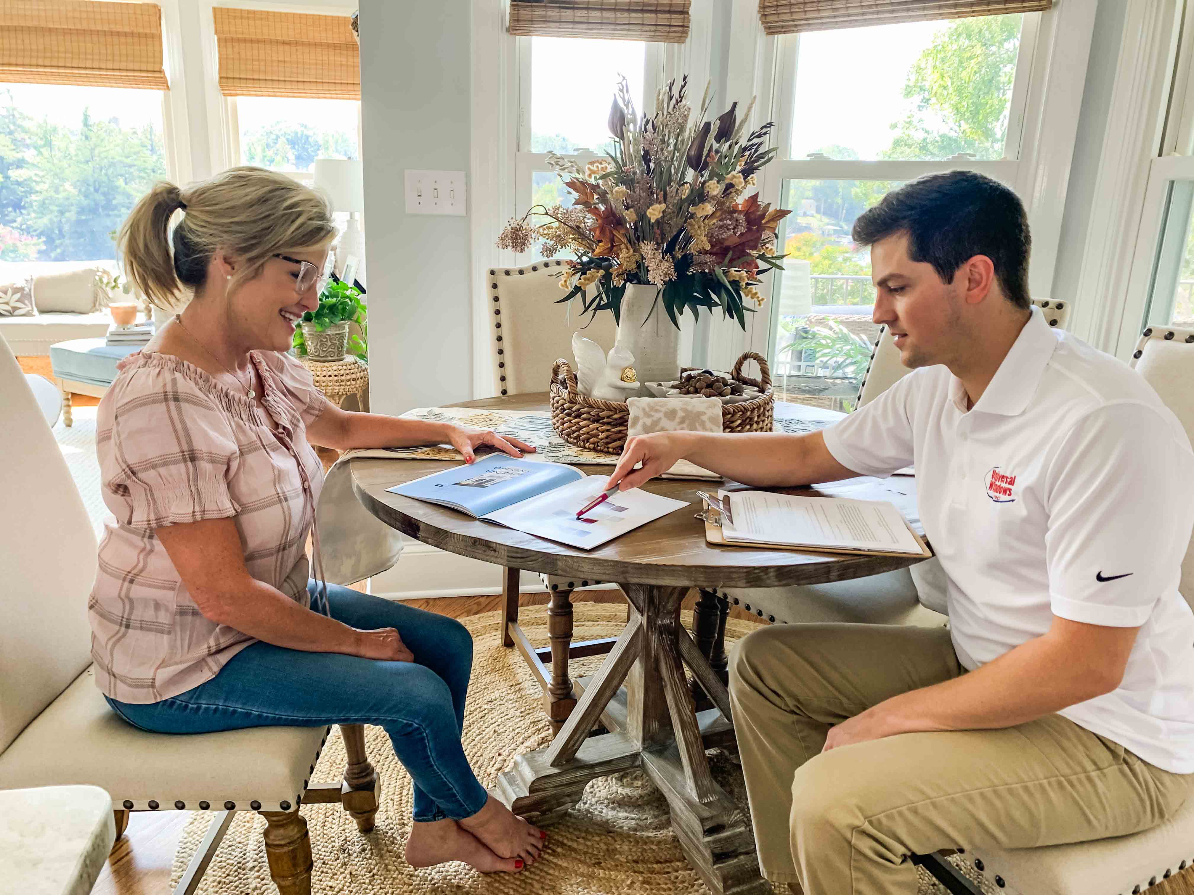 A homeowner reviewing vinyl replacement window warranties with a sales rep
