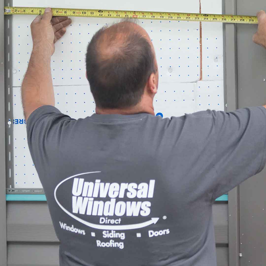 Siding installer measuring siding panels